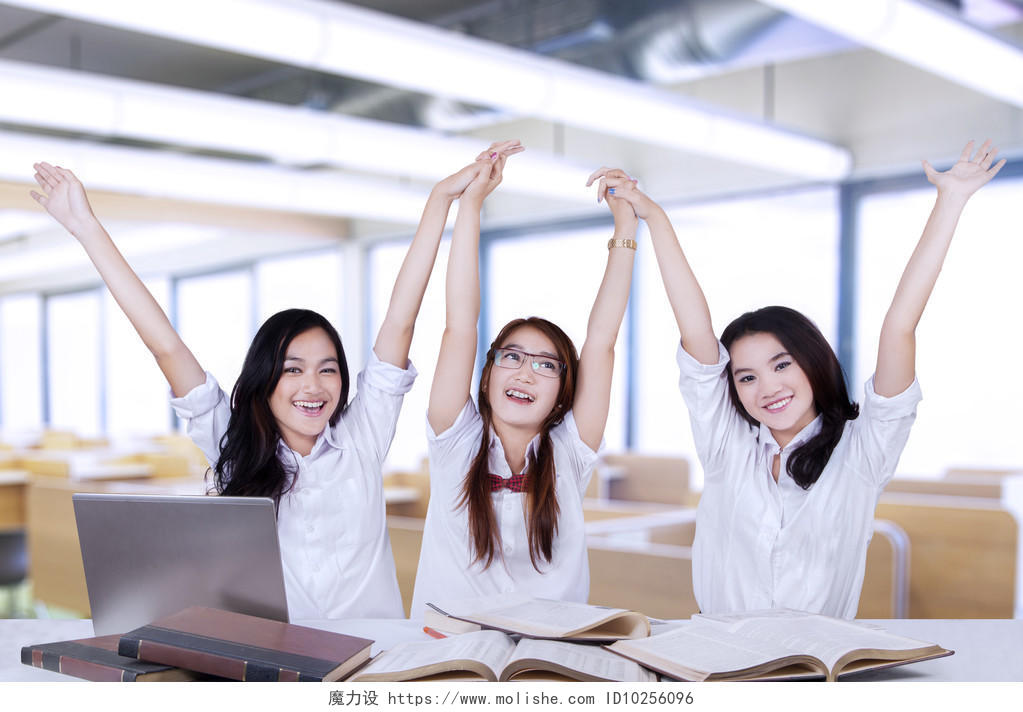 三个成功的女学生在教室里一起举手